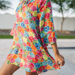 Close up view of Viola Mini Dress with tiered skirt, tie front detail, and ruffled 3/4 sleeves.