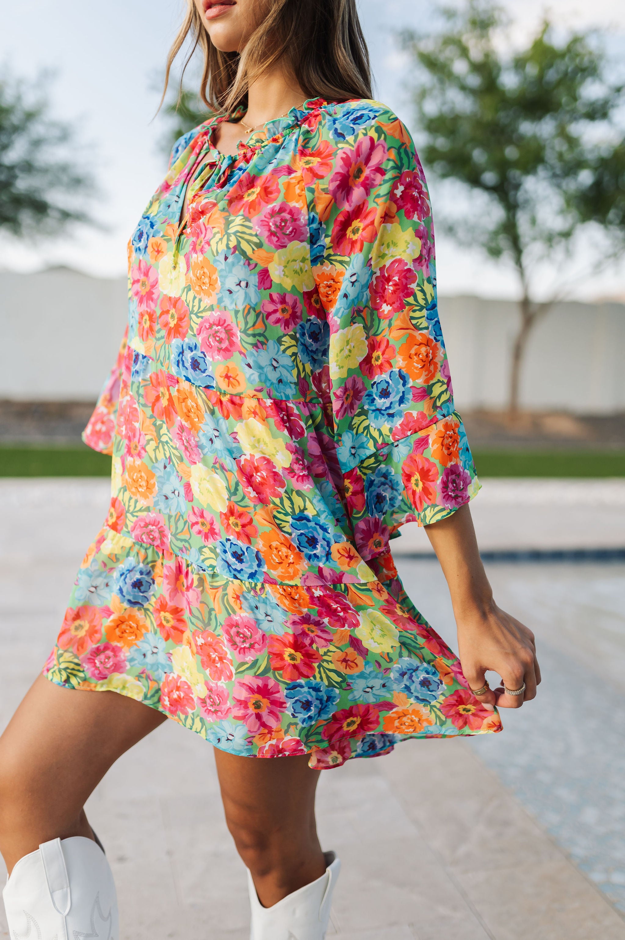 Close up view of Viola Mini Dress with tiered skirt, tie front detail, and ruffled 3/4 sleeves.