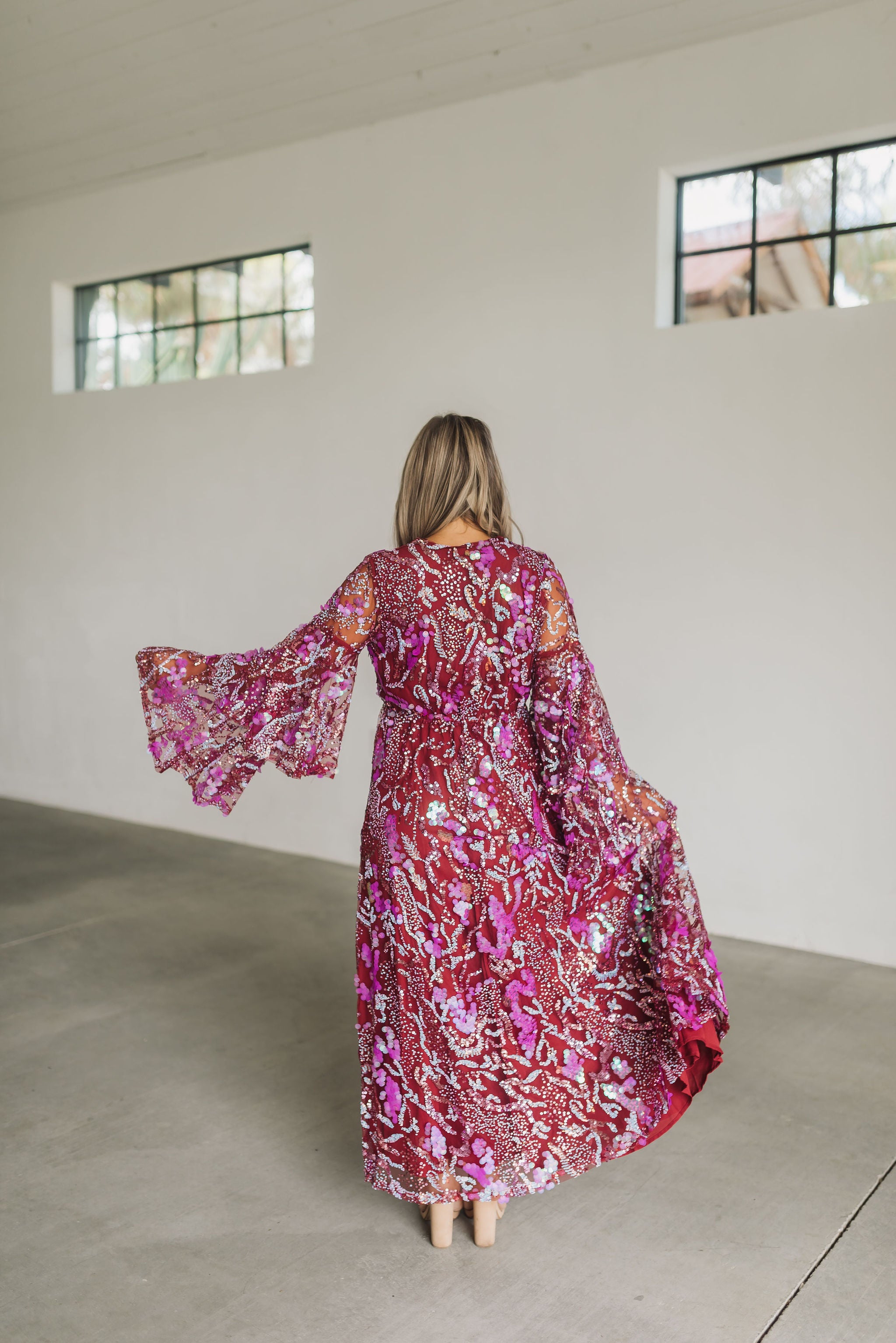 Rear view of Colette Maxi Dress with bell sleeves, empire waist, and allover sequin details.