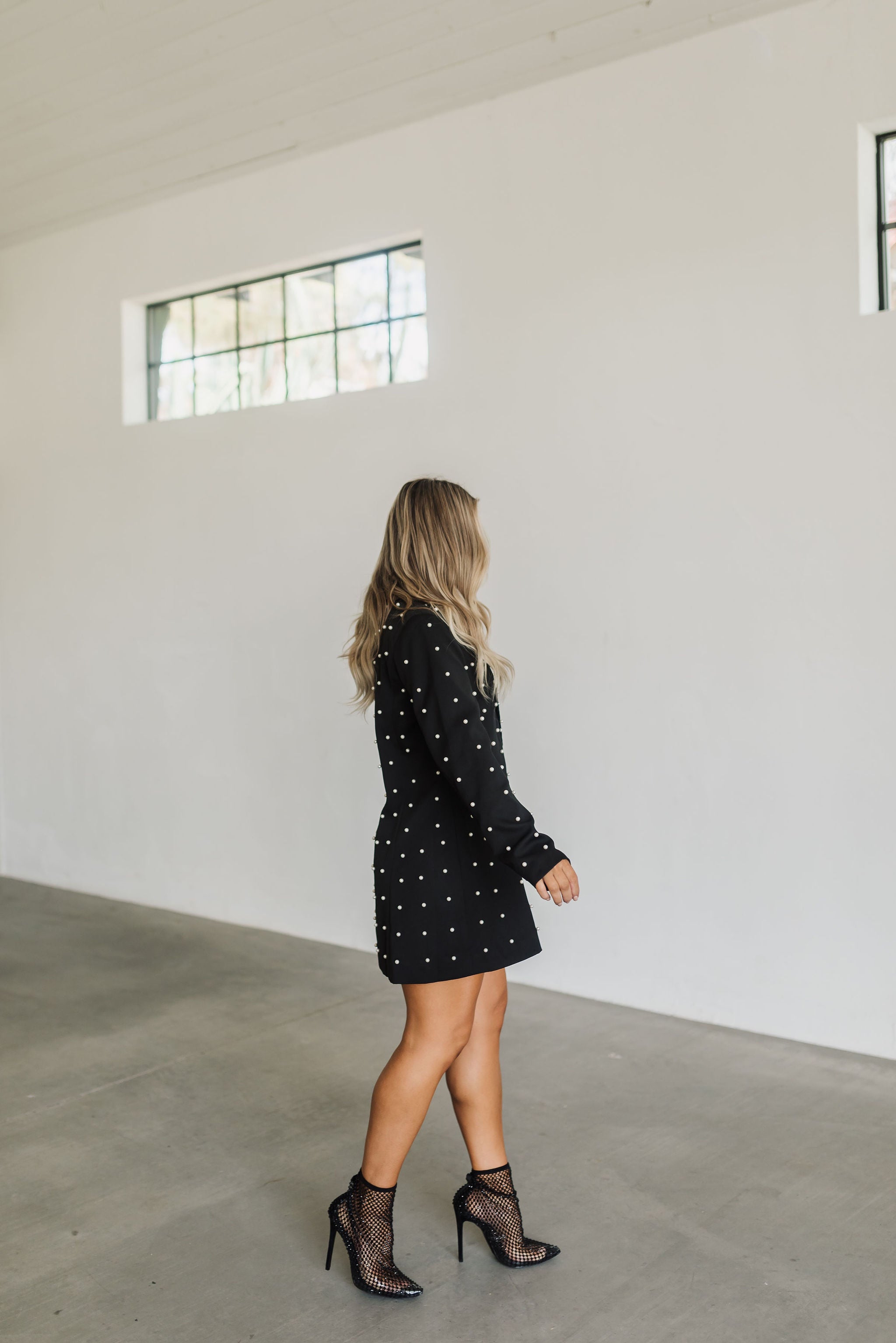 Side view of black long sleeve Riley Blazer Dress with allover pearl detail. 