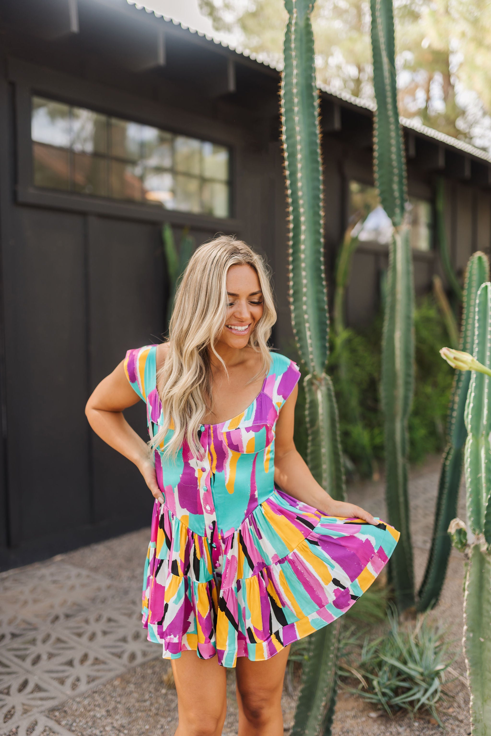 Front view of Elisabeth Romper with allover abstract print, flowy mini skirt, wide straps, and bustier button up front. 