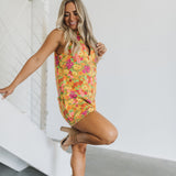 Side view of Reno Romper in allover neon floral print with sleeveless zip up front and collar neck.