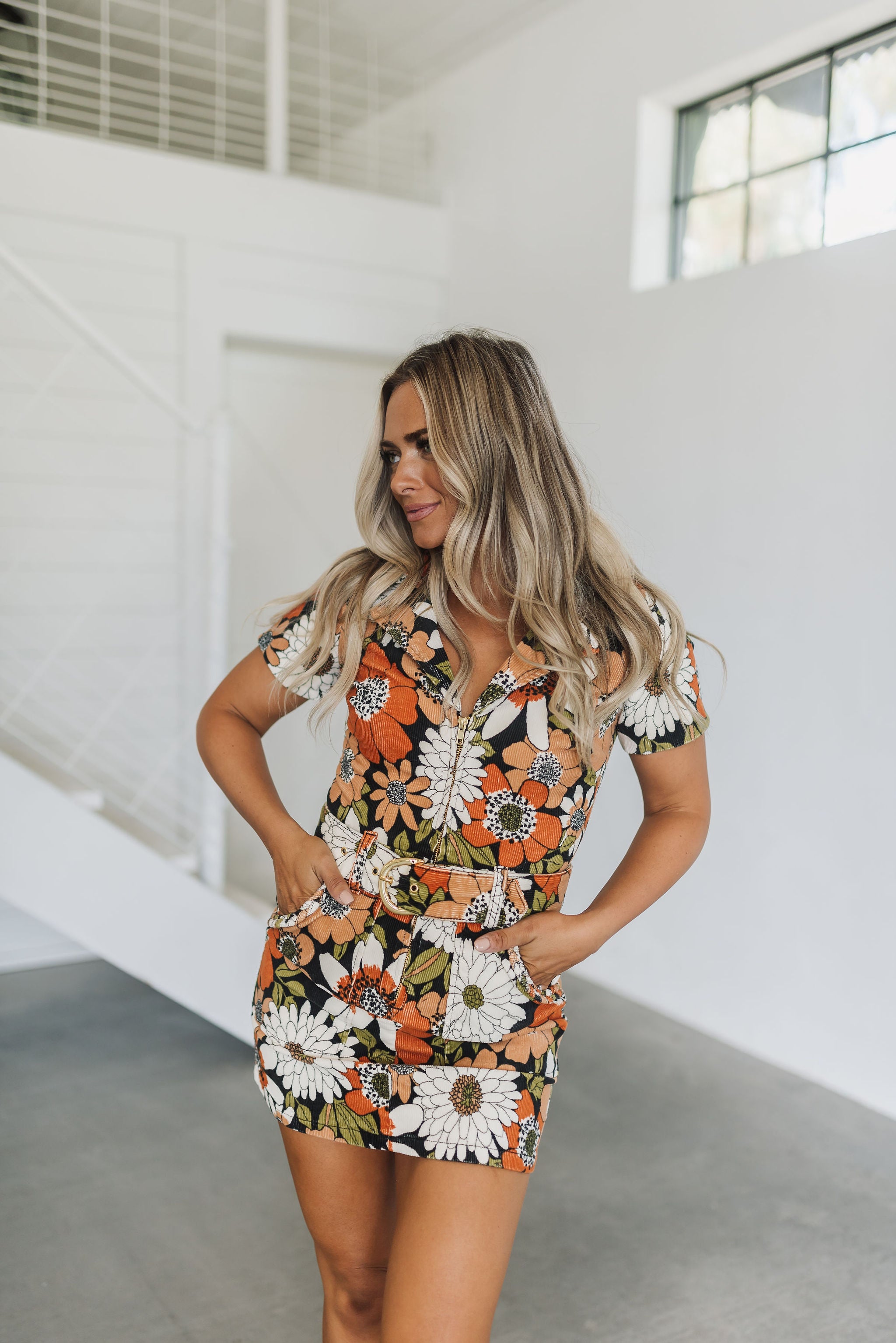 Front view of Outlaw Dress in allover floral corduroy with zip up front, belt, collar neck, and large front pockets. 