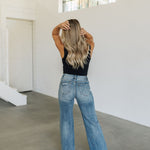 Rear view of Vintage High Rise Wide Leg Jean with whisker wash and distressing on rear pockets and hem.