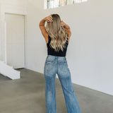 Rear view of Vintage High Rise Wide Leg Jean with whisker wash and distressing on rear pockets and hem.