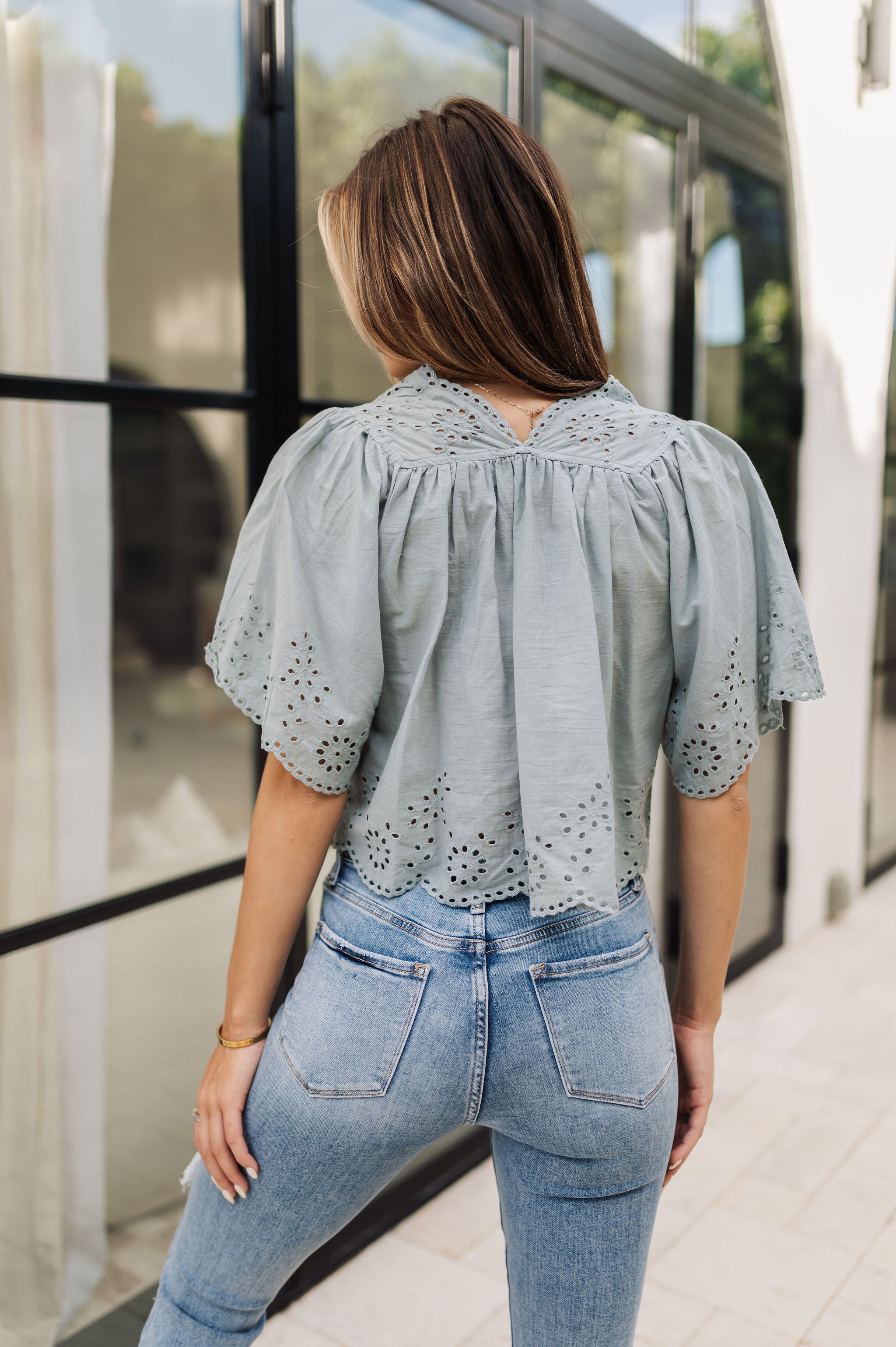 Rear view of Whispering Willow Eyelet Top in faded sage color with eyelet details and scalloped edges and button front.