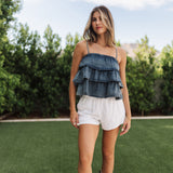 Front view of Ranchers Cascade Tank Top in blue denim color, thin straps, tiered ruffles. 