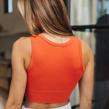 Rear view of Deep Scoop Crop Top in a burnt sienna color with banded hem. 