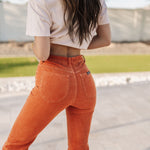 Up close rear view of Eastcoast Flare Cord pants in a rust color with flared legs and rear pockets. 