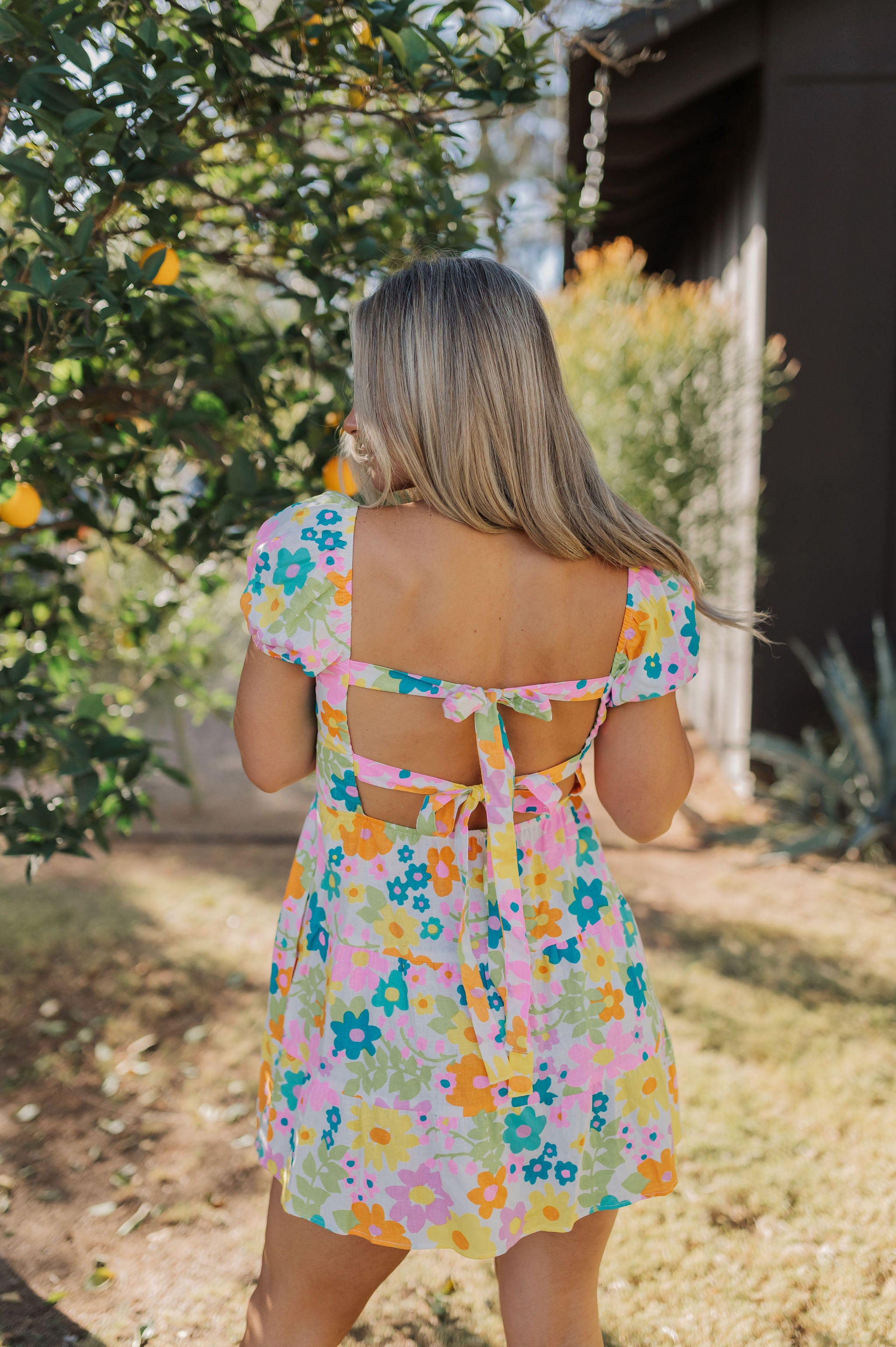 Rear view of Cathy Mini Dress in allover floral print, puff sleeves, and double tie back.