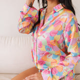 Seated view of Early Riser PJ Set with candy heart graphic and button down top.