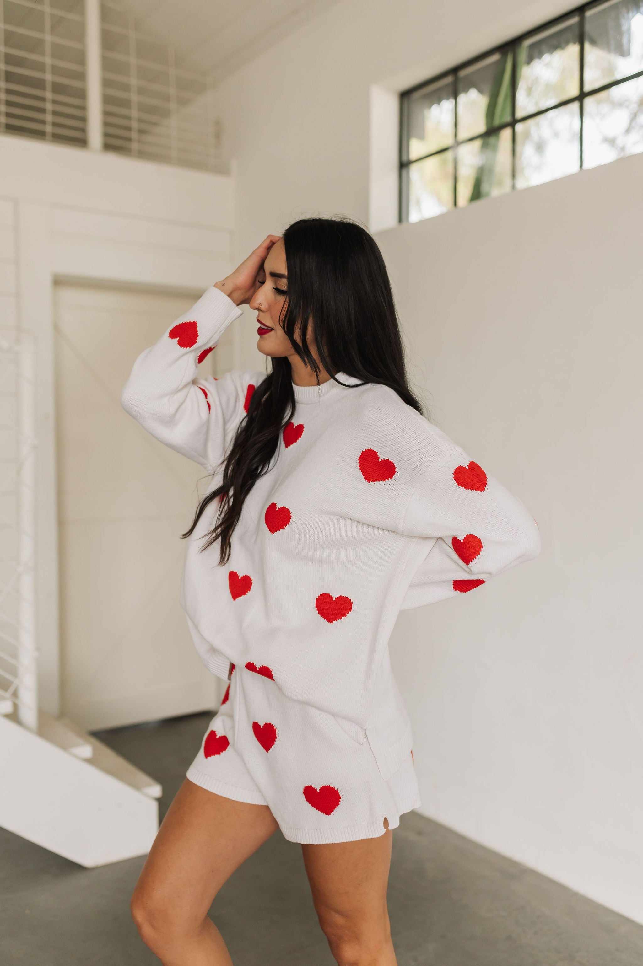 Side view of white Boardwalk Shorts with red hearts print and ribbed hemline. 