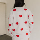 Rear view of white crewneck Go To Sweater with red hearts print and ribbed hemline. 