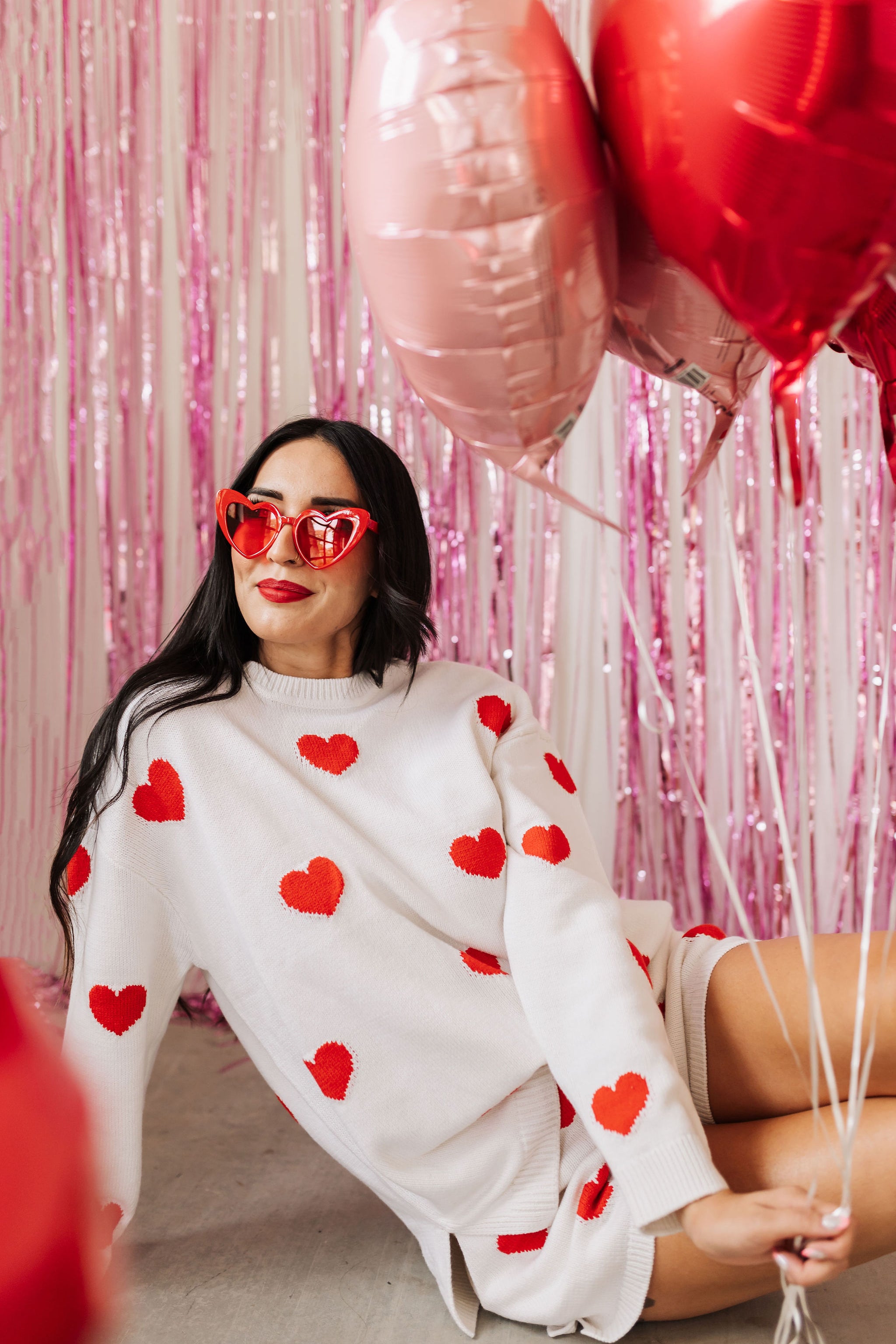 Front angled view of white crewneck Go To Sweater with red hearts print and ribbed hemline. 