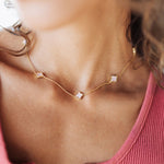 Close-up of a person wearing a delicate gold necklace with small stones.
