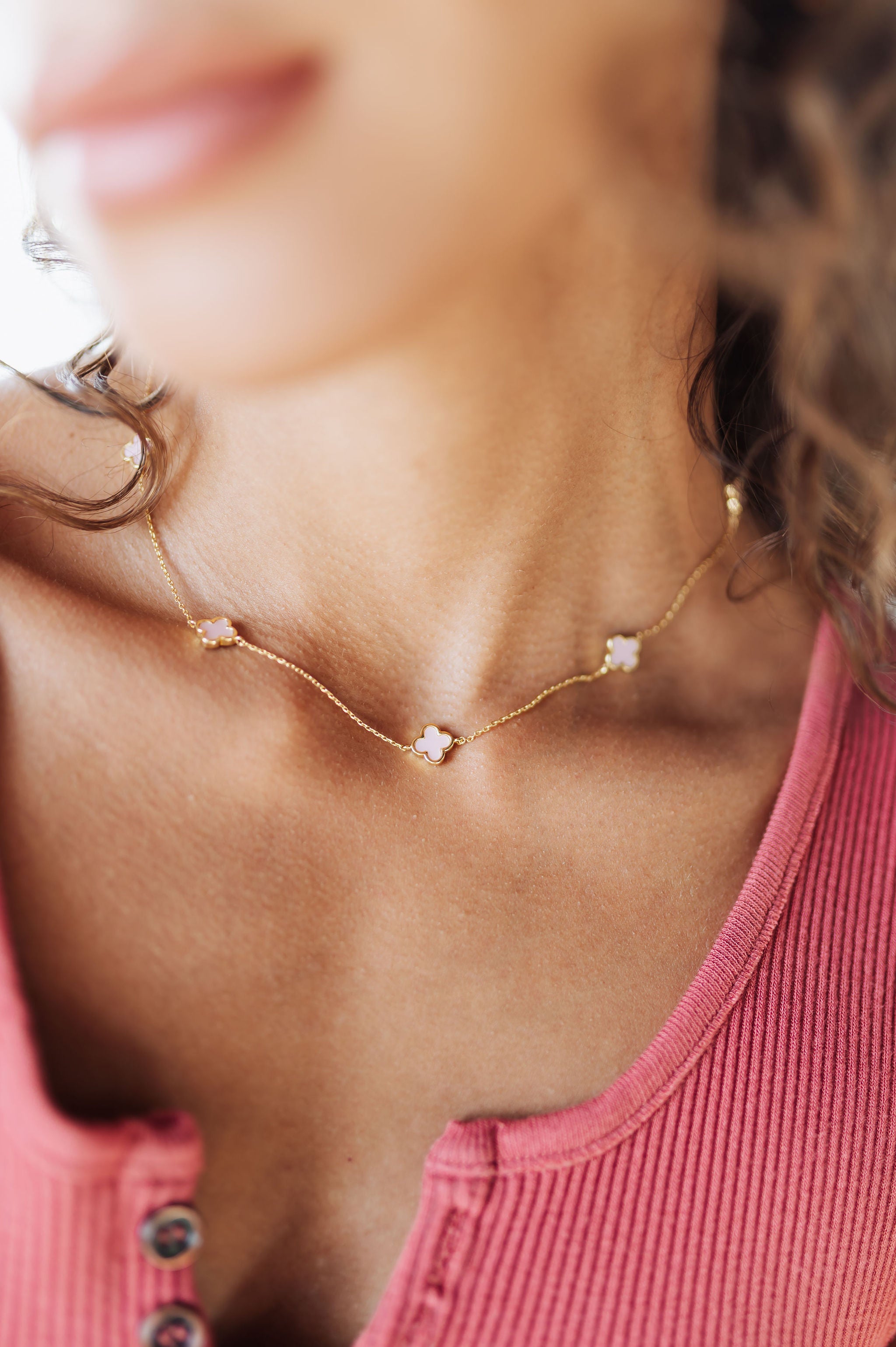 Close-up of a person wearing a delicate gold necklace with small stones.