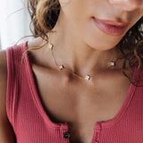 Close-up of a woman wearing a pink ribbed tank top and a delicate necklace with small stones.