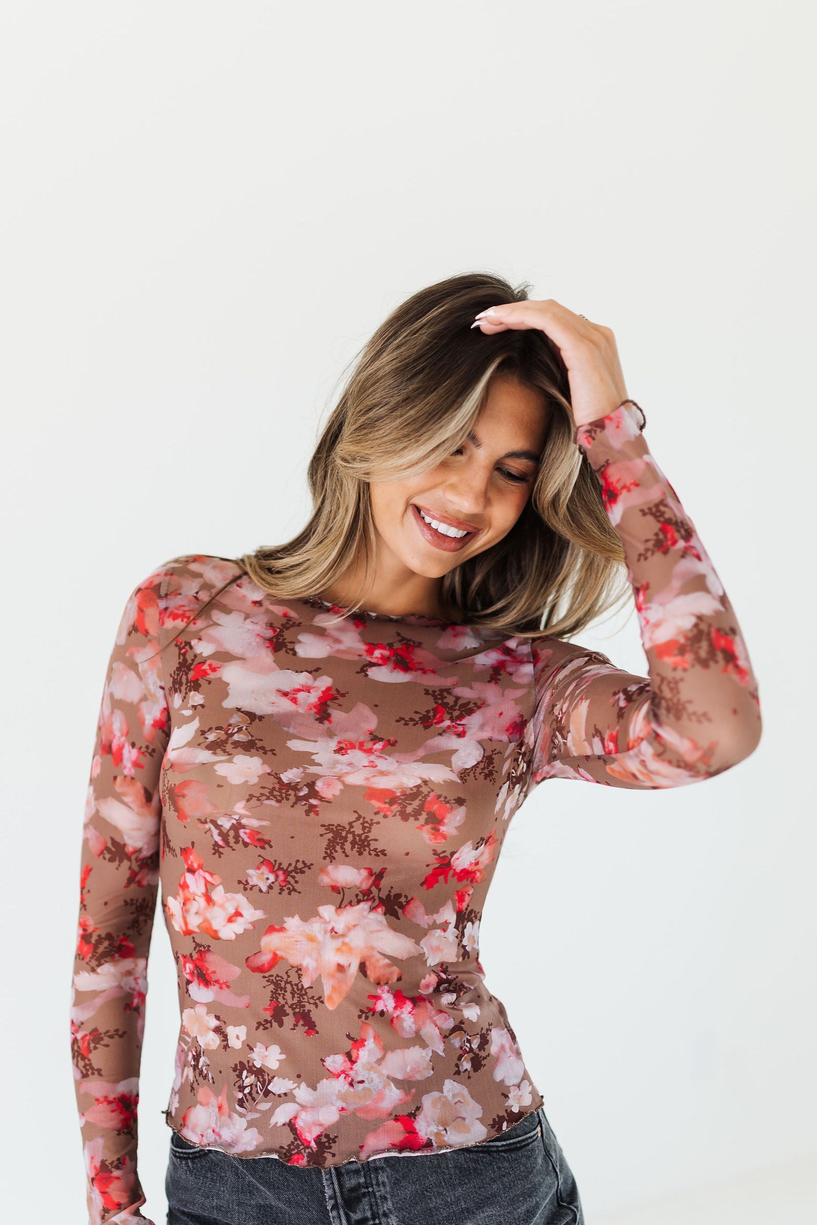 Woman wearing a floral long-sleeve top against a white background