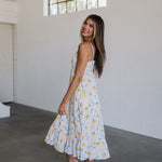 Side view of Summer Fling Midi Dress with embroidered Limoncello print, thin straps, square neckline, side pockets, and ruffled hem.