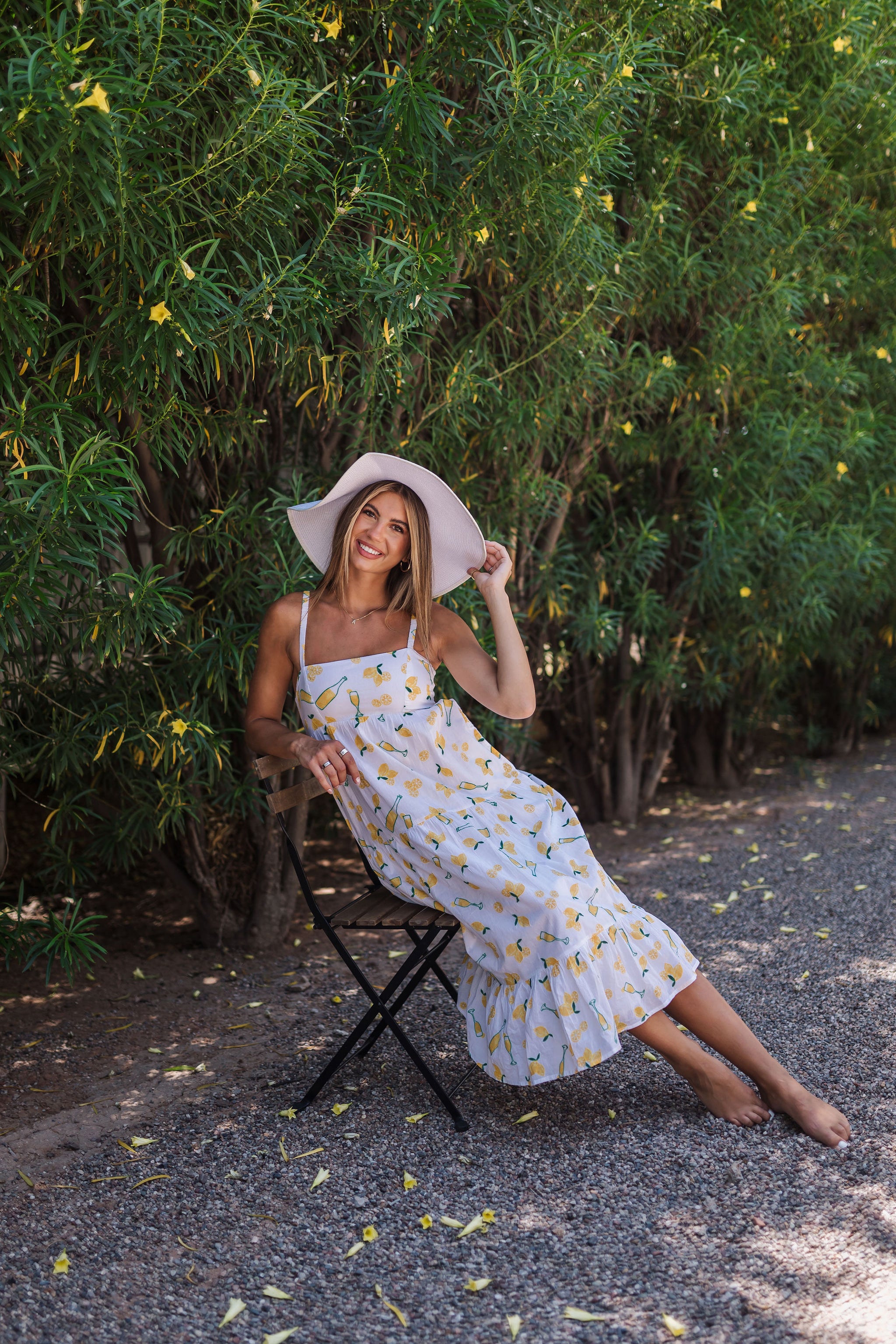 Seated view of Summer Fling Midi Dress with embroidered Limoncello print, thin straps, square neckline, and ruffled hem. 