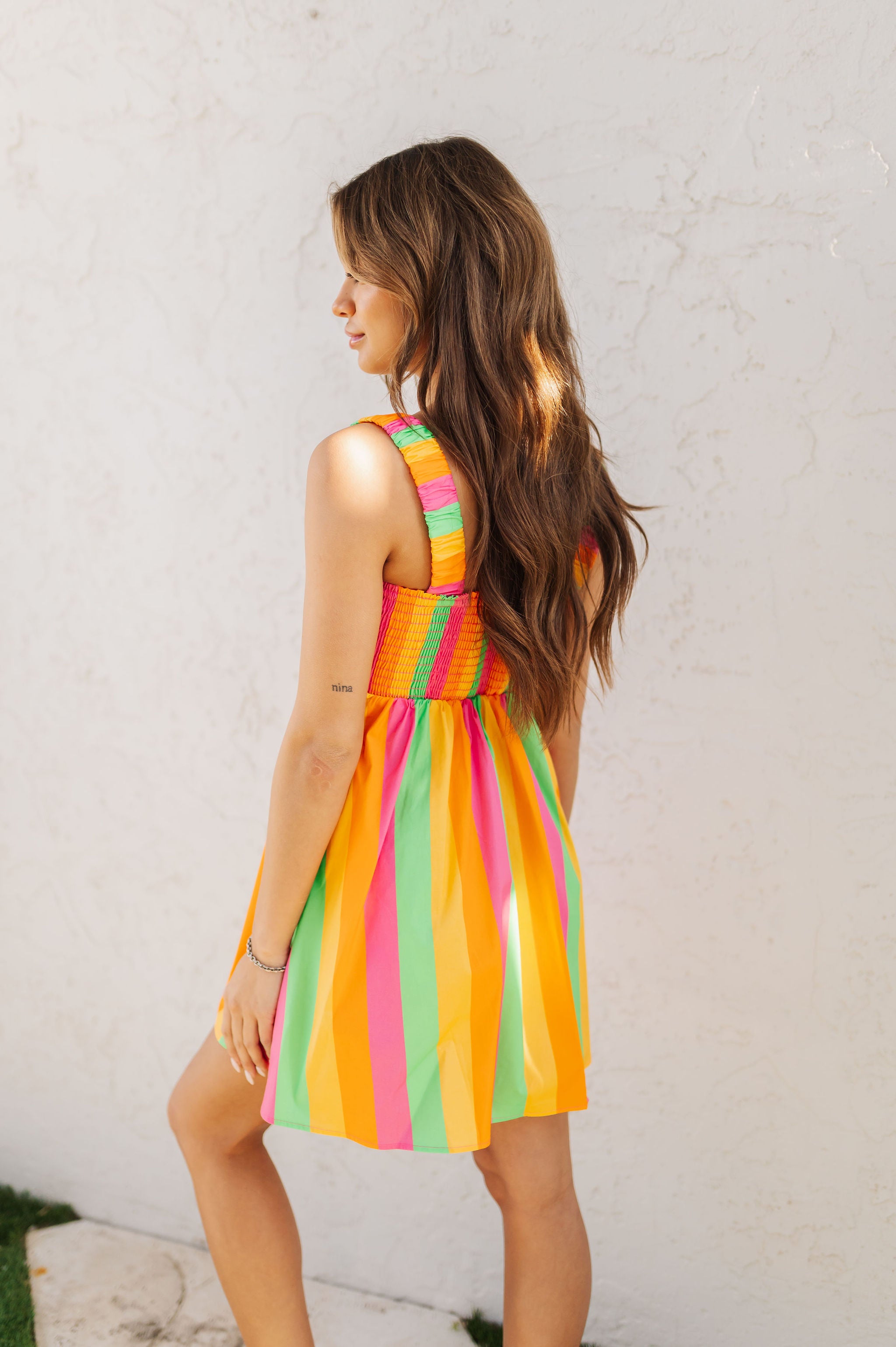 Rear angled view of neon striped Fling Mini Dress with smocked straps and back.