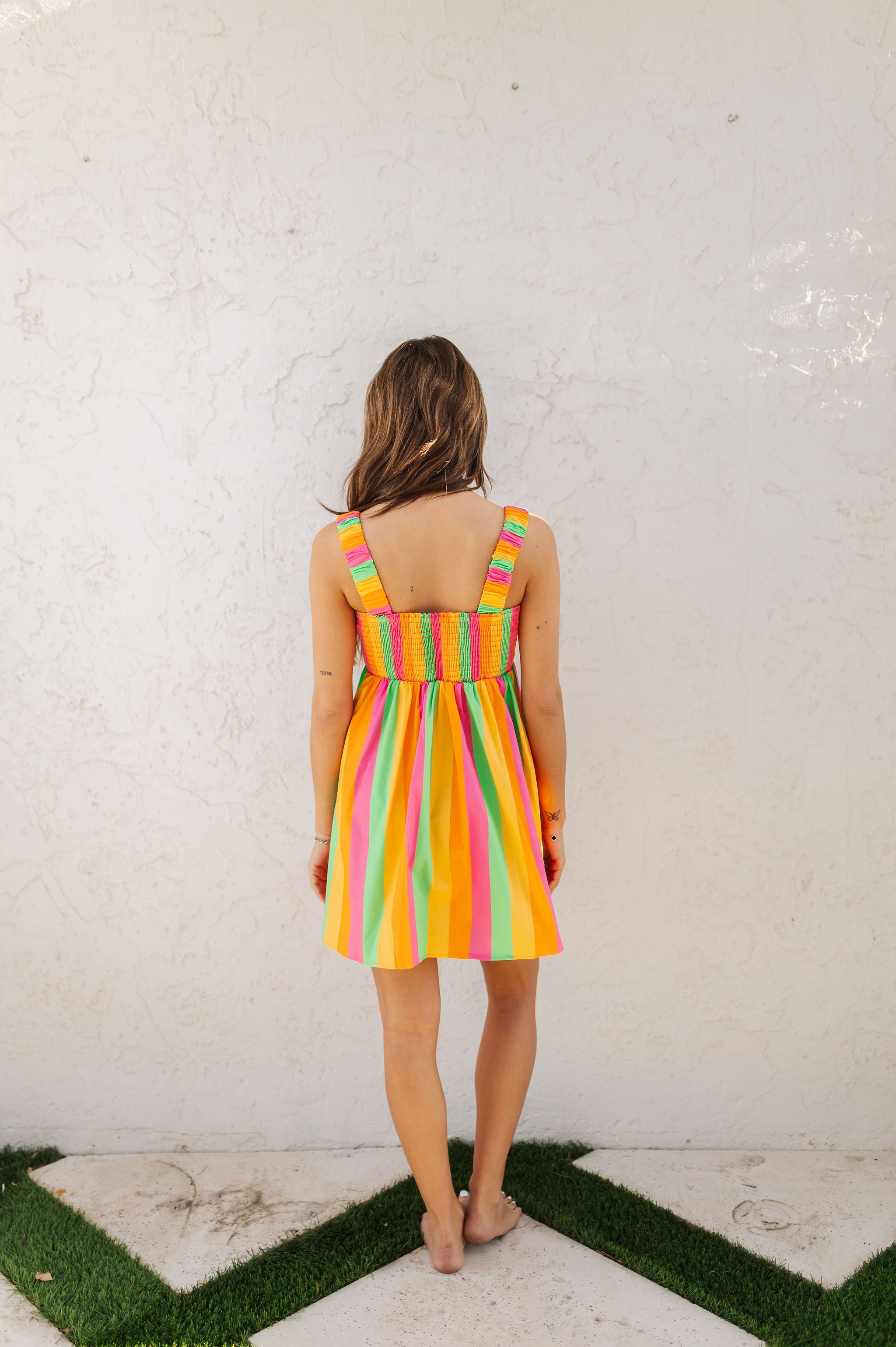 Rear view of neon striped Fling Mini Dress with smocked straps and back.
