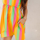 Close up front view of neon striped Fling Mini Dress with smocked straps and side pockets.