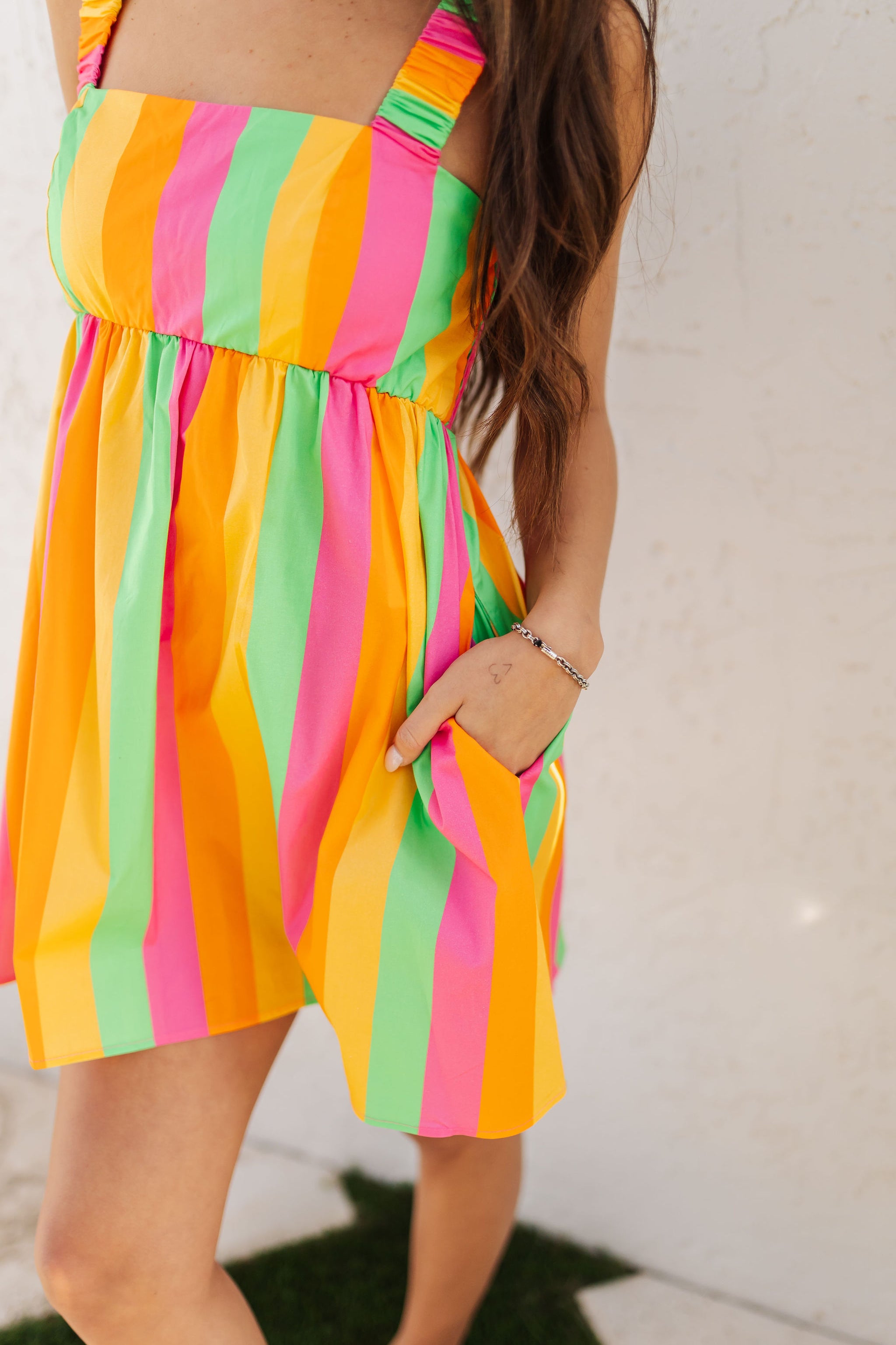 Close up front view of neon striped Fling Mini Dress with smocked straps and side pockets.