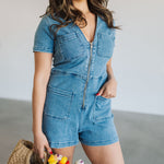 Front view of  Ranch Romper in blue with zippered front, patch pockets on the chest and hip, and collared top. 