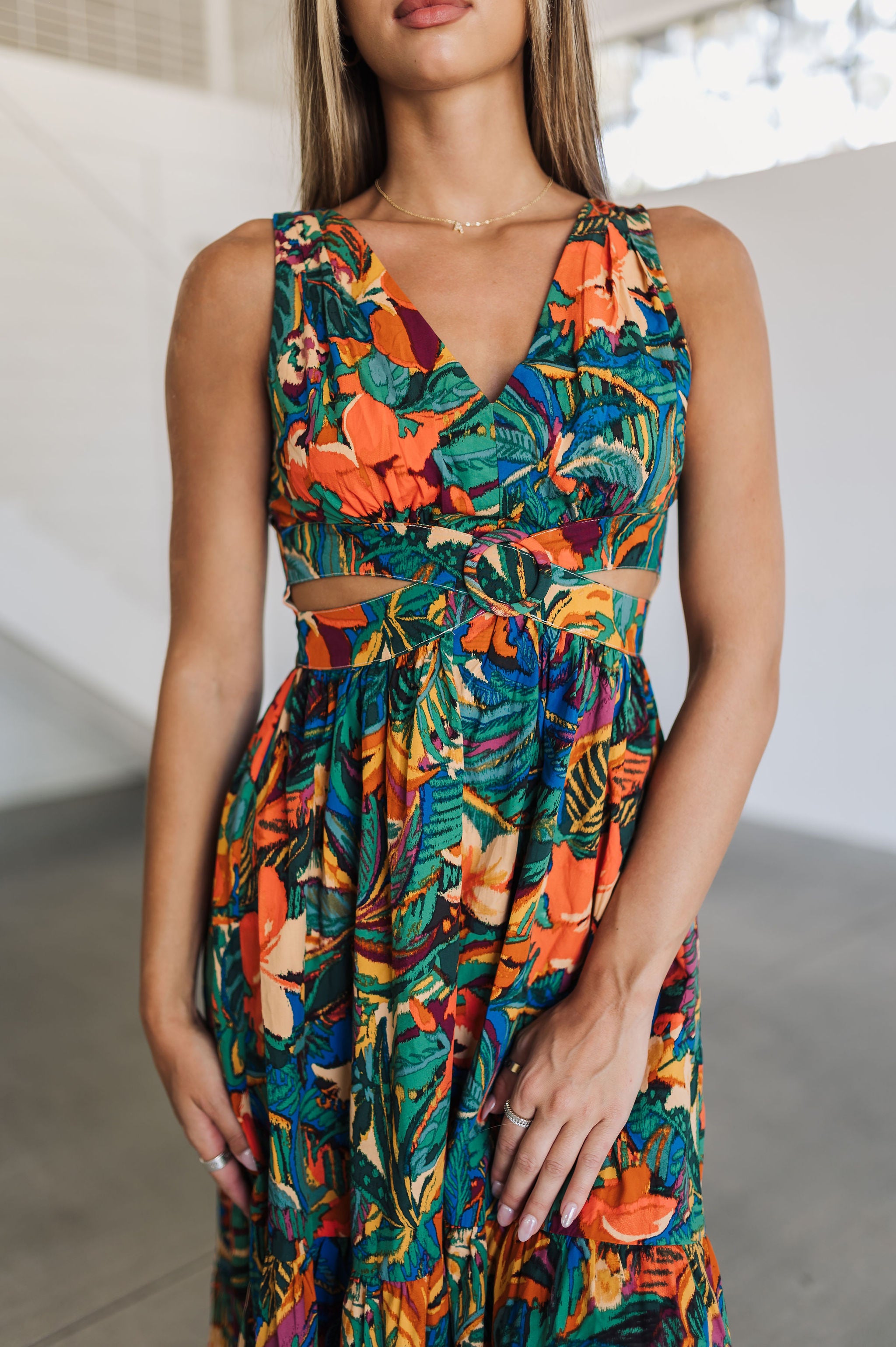 Close up front view of Tropical Isle Cut Out Midi Dress with allover floral print, V-neck, wide shoulder straps, and side cutouts. 