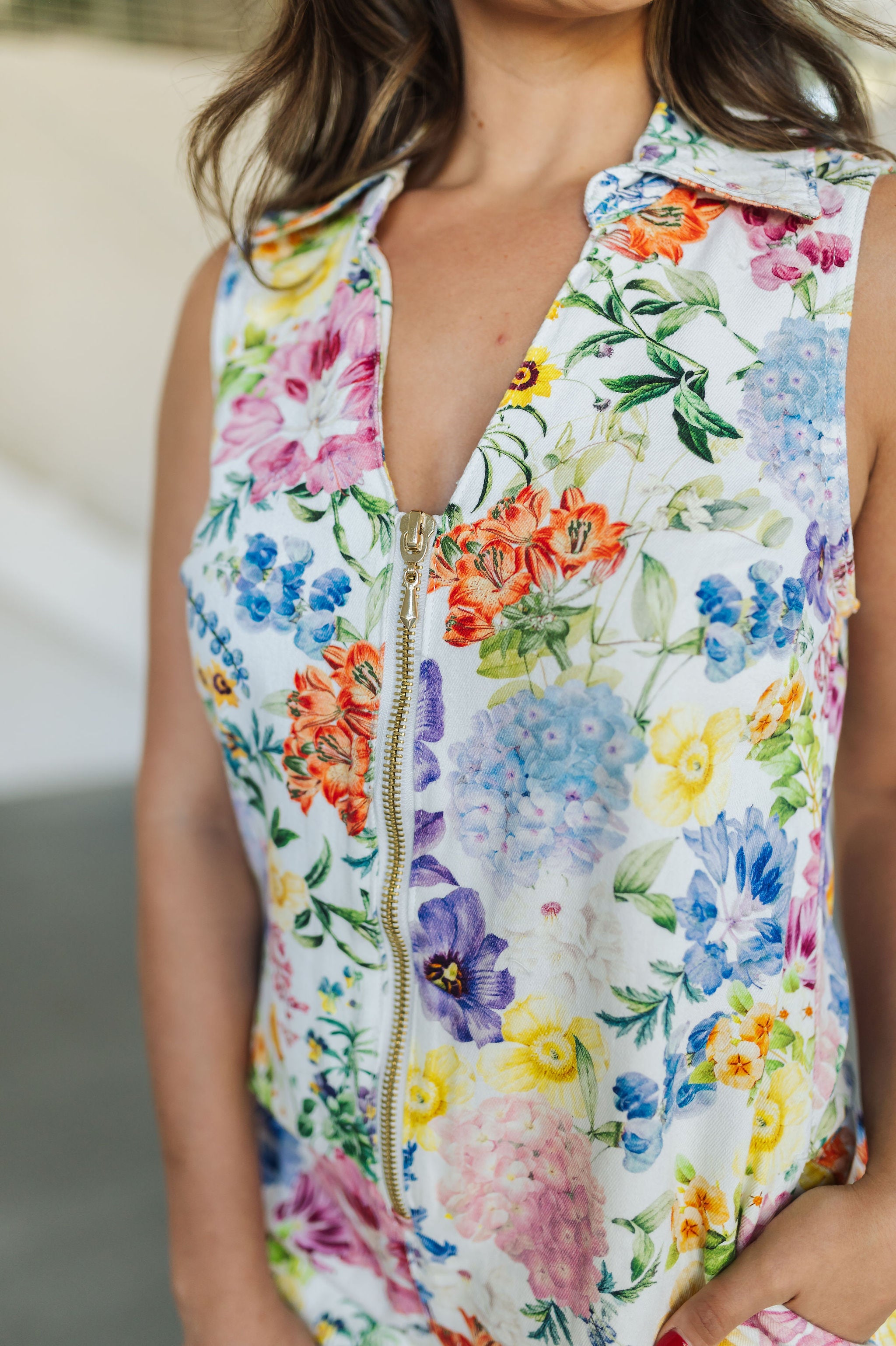 Close up front view of sleeveless Reno Romper in allover floral print, zip up front, and collared neckline. 