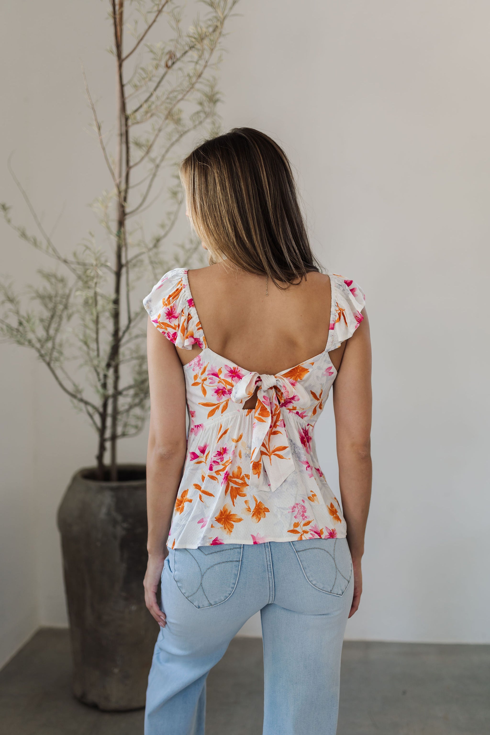 Rear view of Azalea Tie Back Tank Top with flutter straps, tie back closure, and neon floral print. 