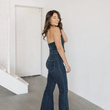Side view of Fort Worth Jumpsuit in blue with belted waist, embroidered rear pocket, halter top, and flared leg. 