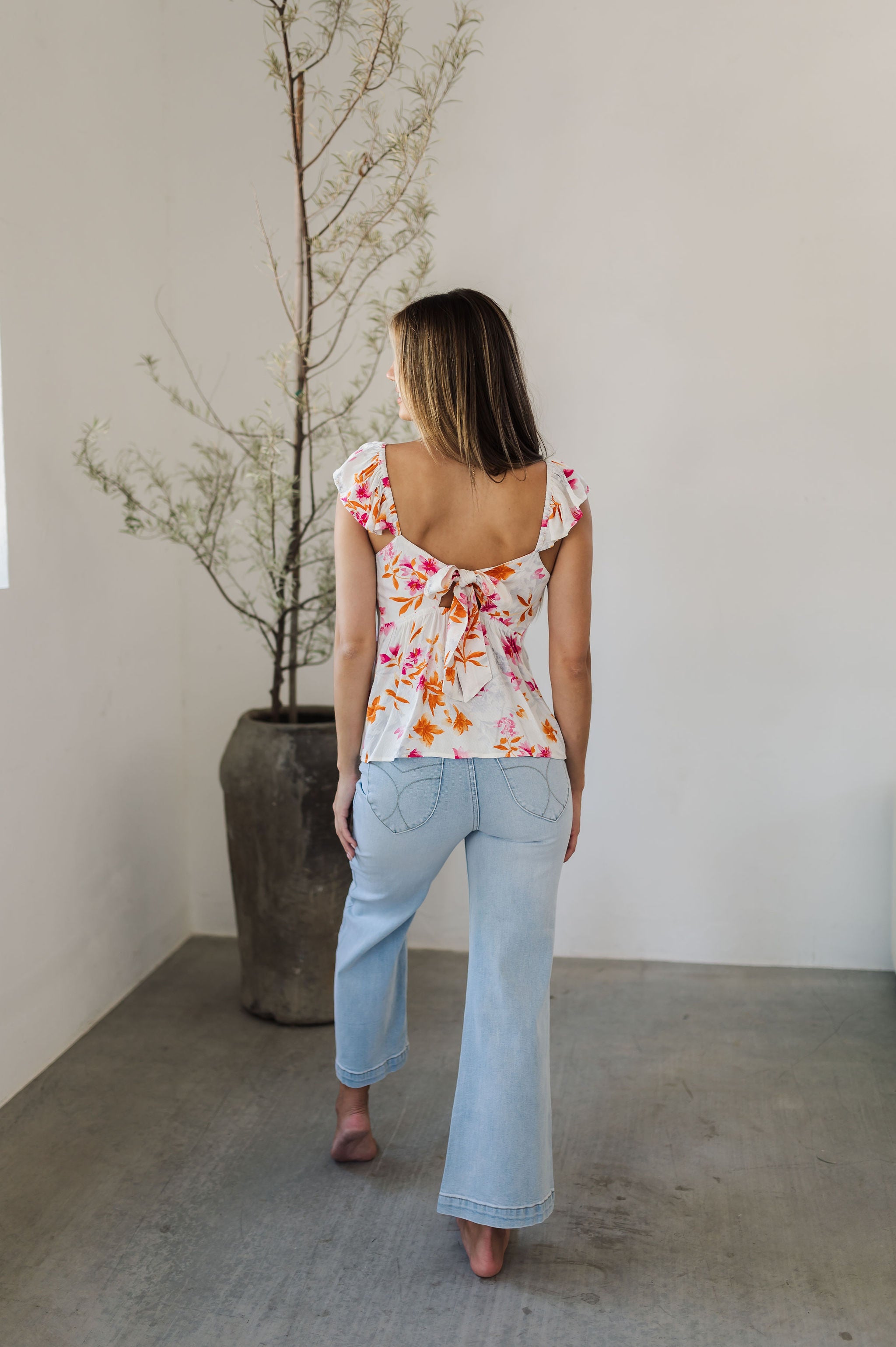 Rear view of Azalea Tie Back Tank Top with flutter straps, tie back closure, and neon floral print.