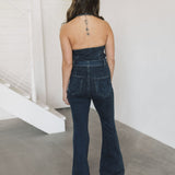 Rear view of Fort Worth Jumpsuit in blue with belted waist, embroidered rear pockets, halter top, and flared lg. 