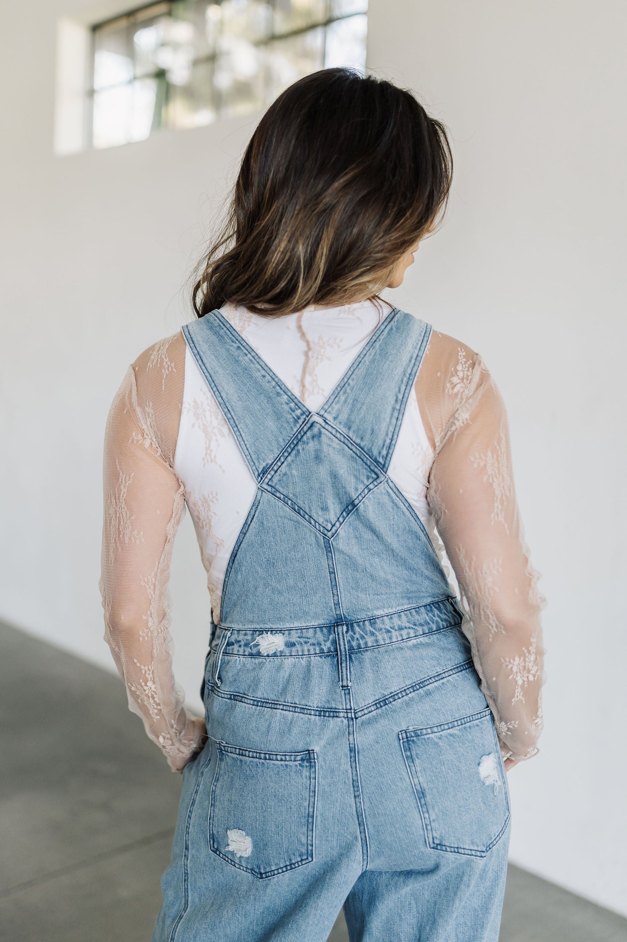  Rear view of nude Daisy Sheer Lace Long Sleeve Top paired with cropped tank. 