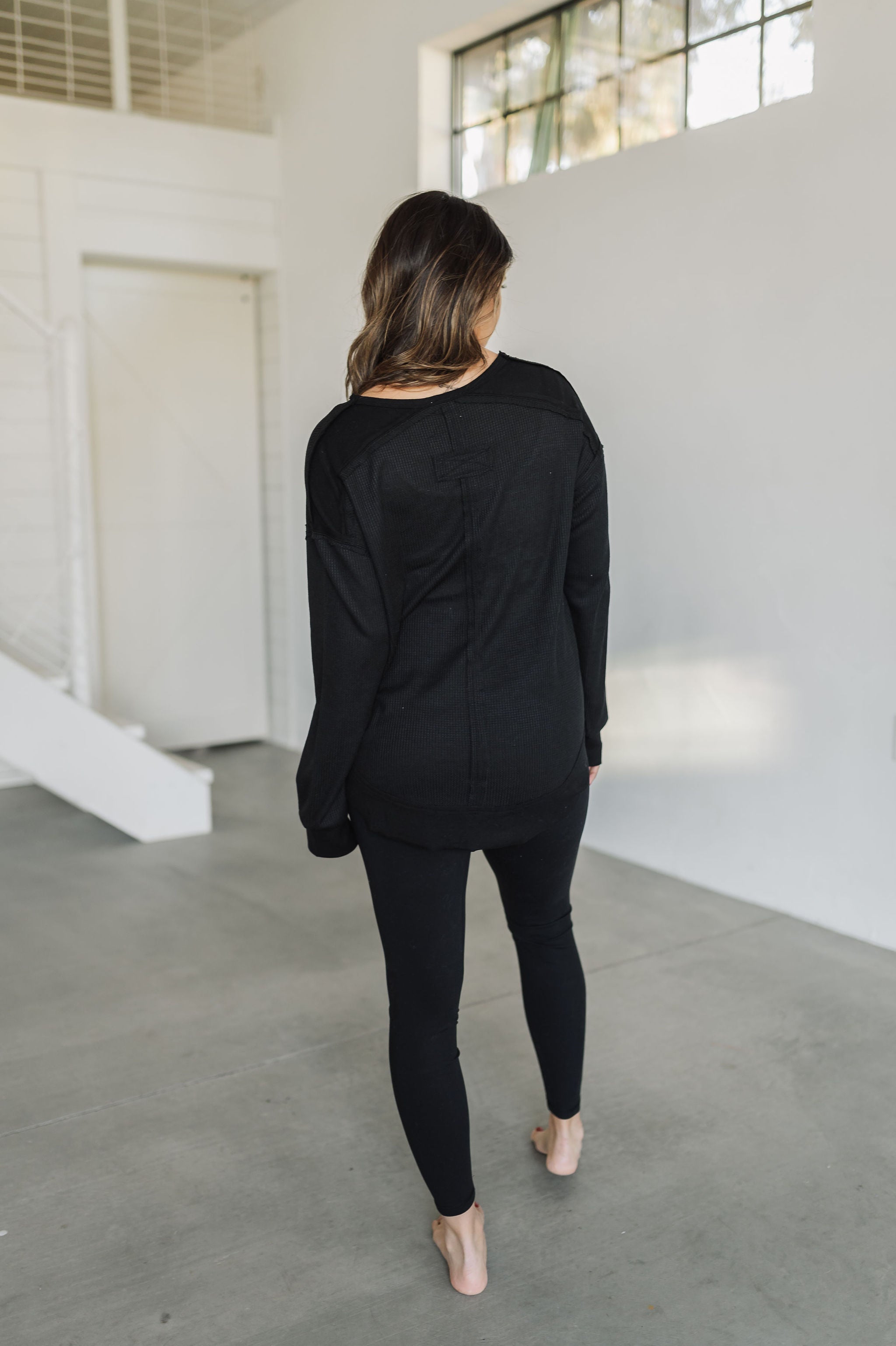 Rear view of black Auden V-Neck Long Sleeve Top with waffle-knit design.