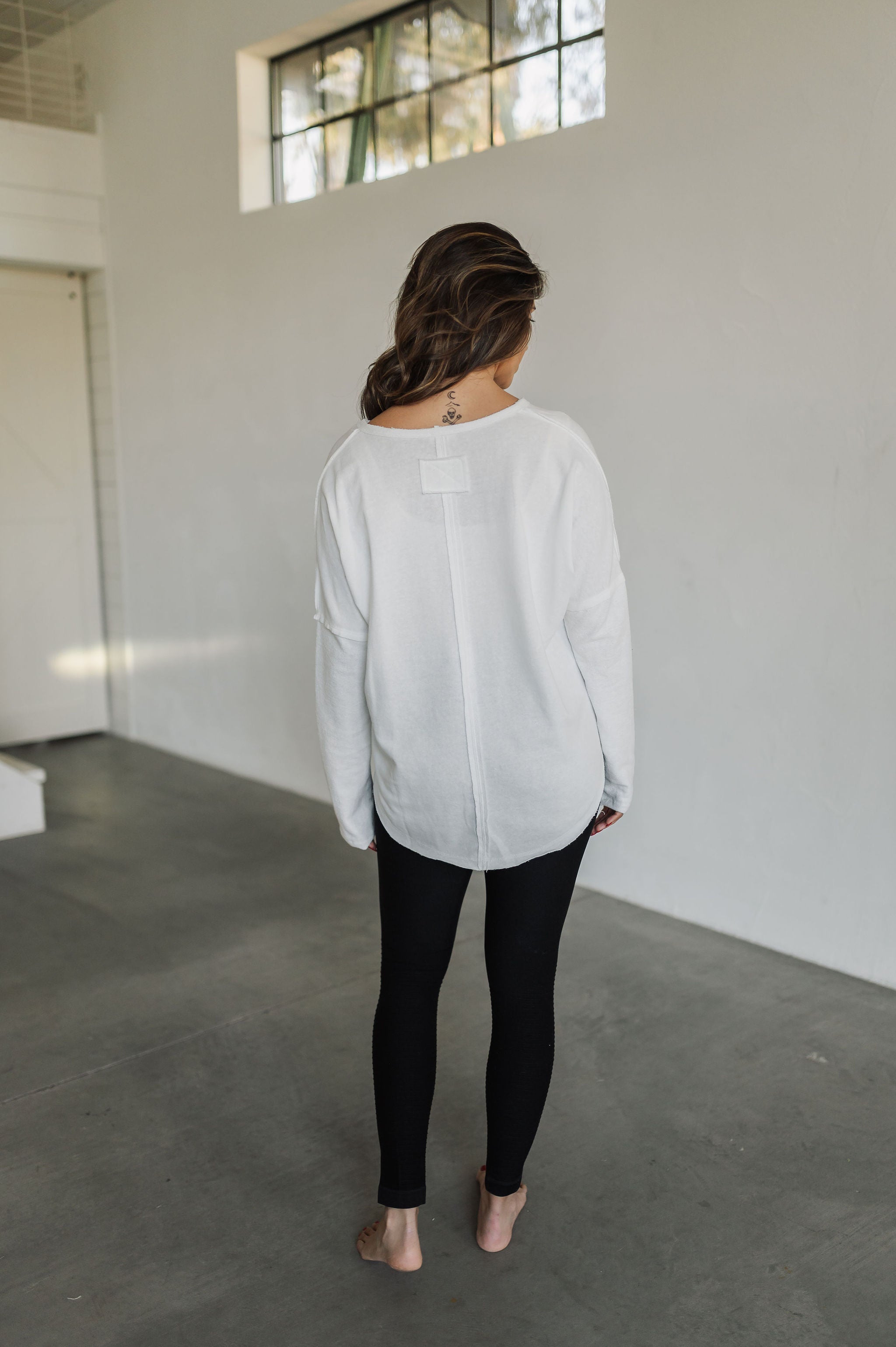 Rear view of Harper Long Sleeve Top with raw hem. 