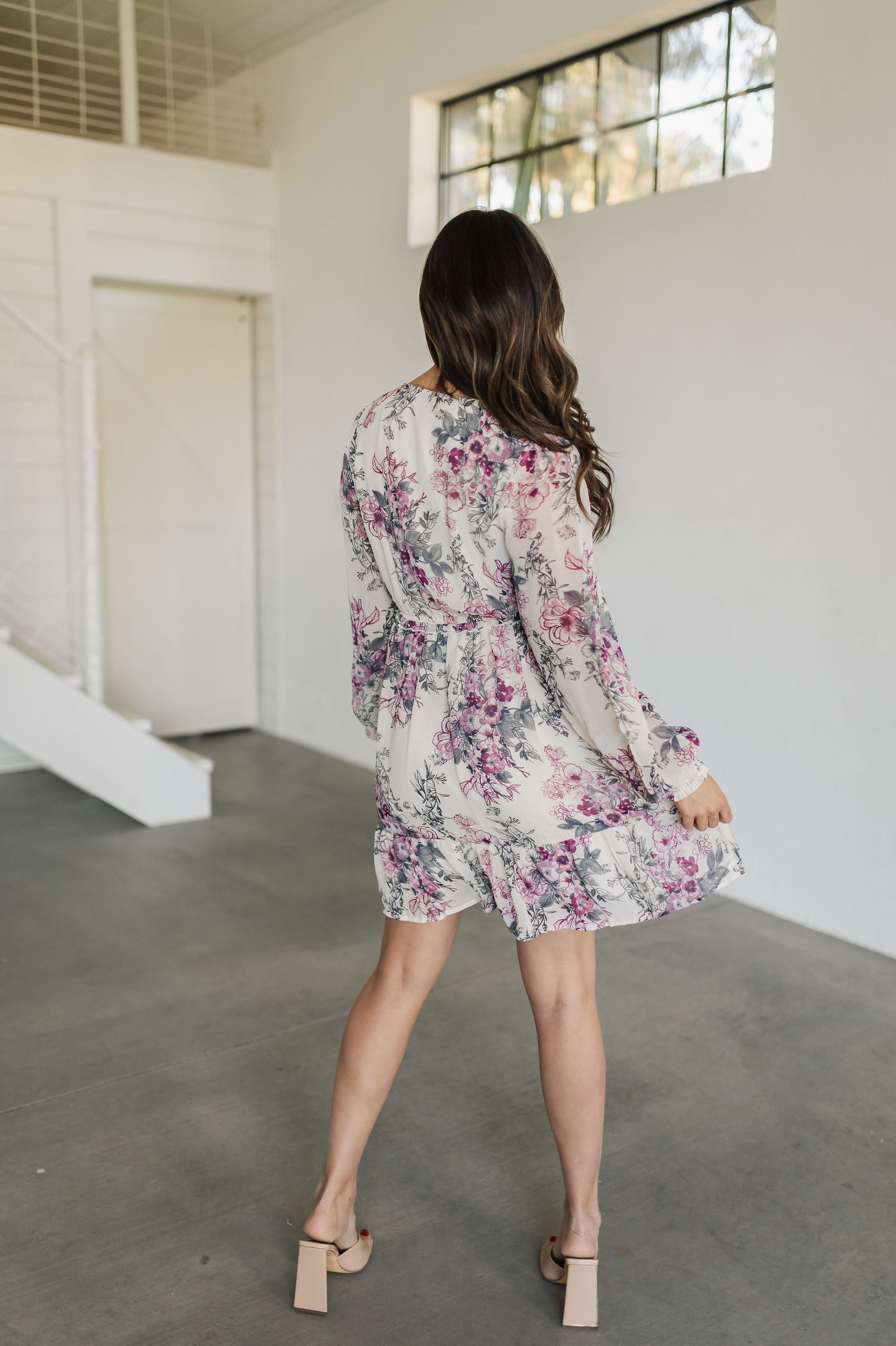 Rear view of Aster Floral Mini Dress with long sleeves and ruffled hem. 
