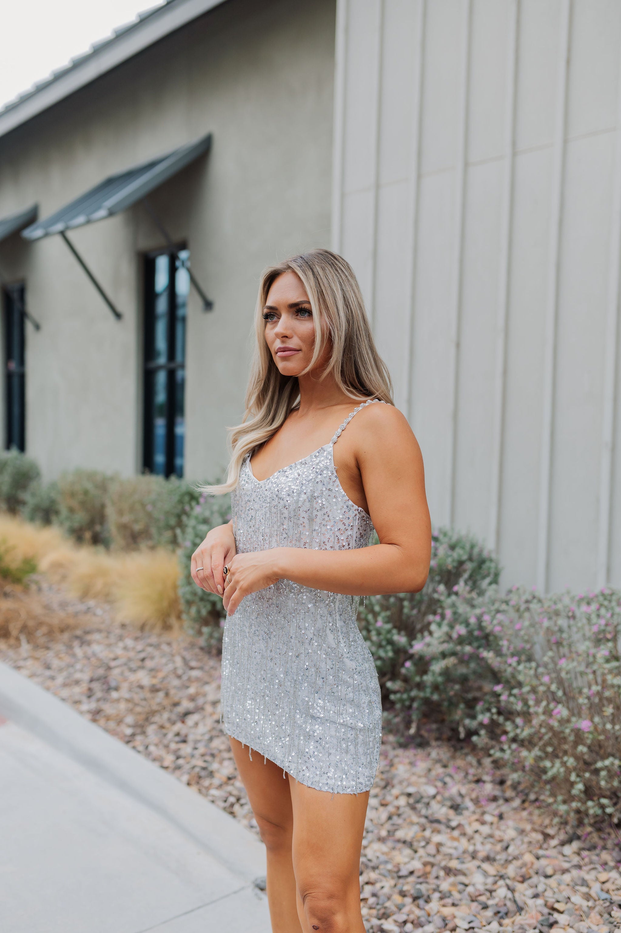 Front angled view of Sparks Fly Mini Dress with thin straps and allover fringe and sequin details. 