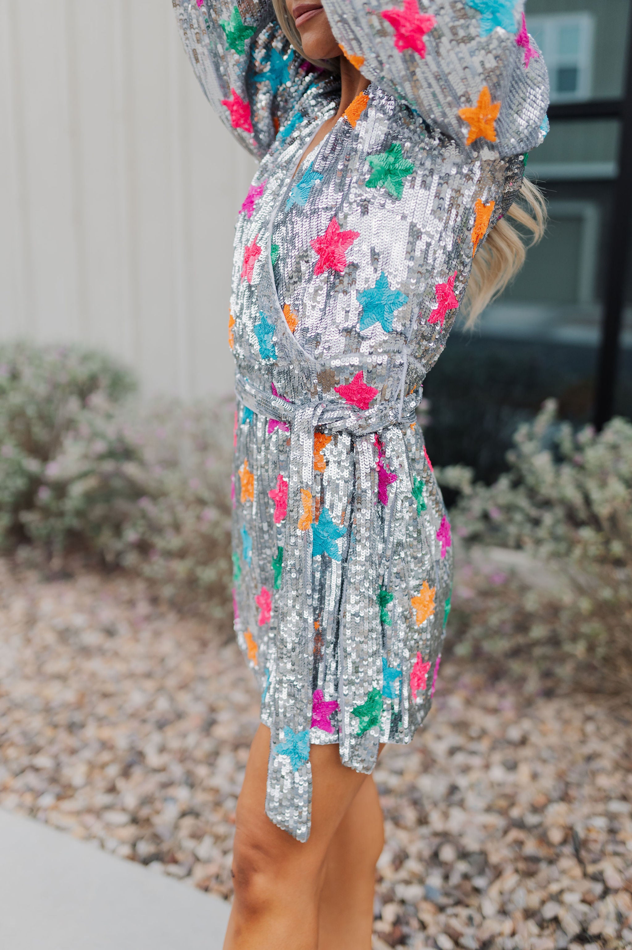 Side view of Wear Me Out Dress with wrap waist, long bubble sleeves, and allover star print in sequins.  