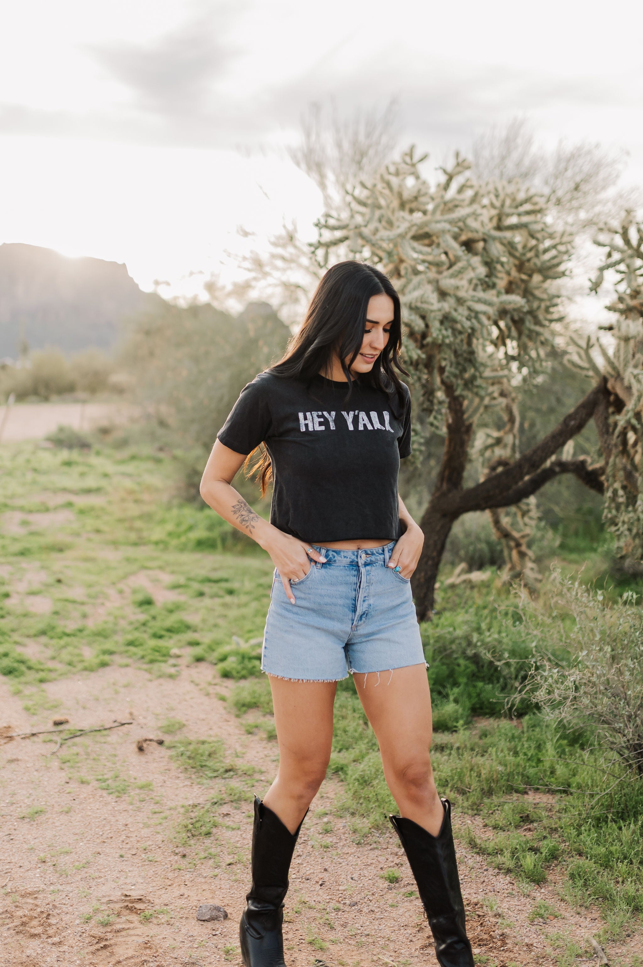 Front angled view of Hey Y'all Graphic Tee in mineral wash, distressed graphic, and raw hem. 