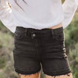 Front view of distressed Rebecca Shorts with cross-over waistband and raw hem. 