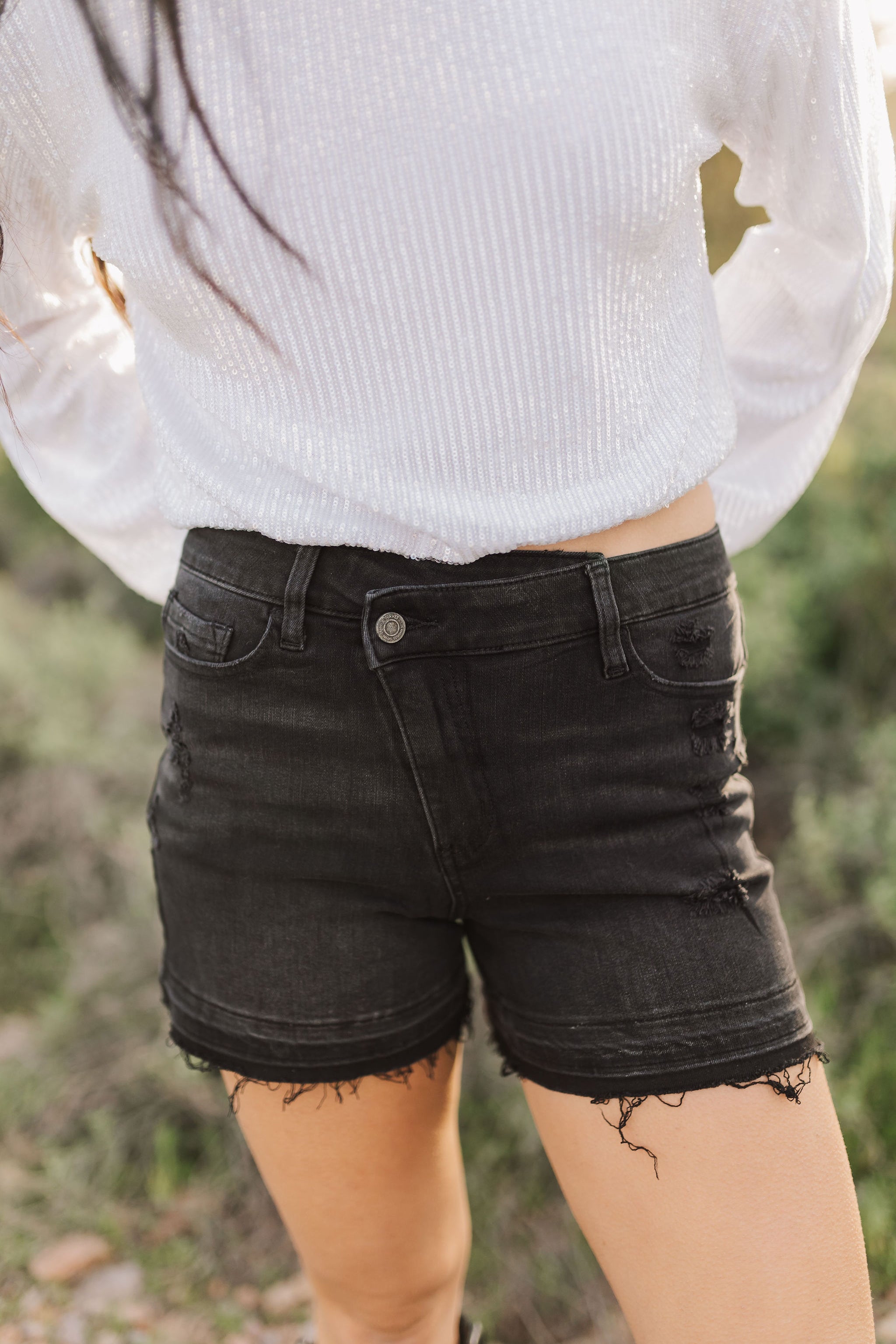 Front view of distressed Rebecca Shorts with cross-over waistband and raw hem. 