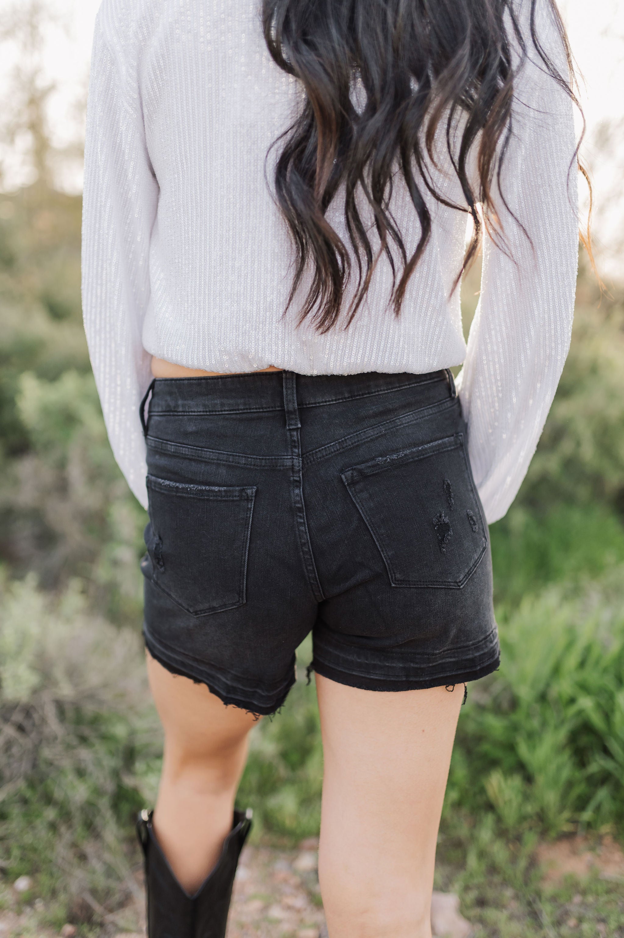 Close up rear view of distressed Rebecca Shorts with rear pockets and raw hem.