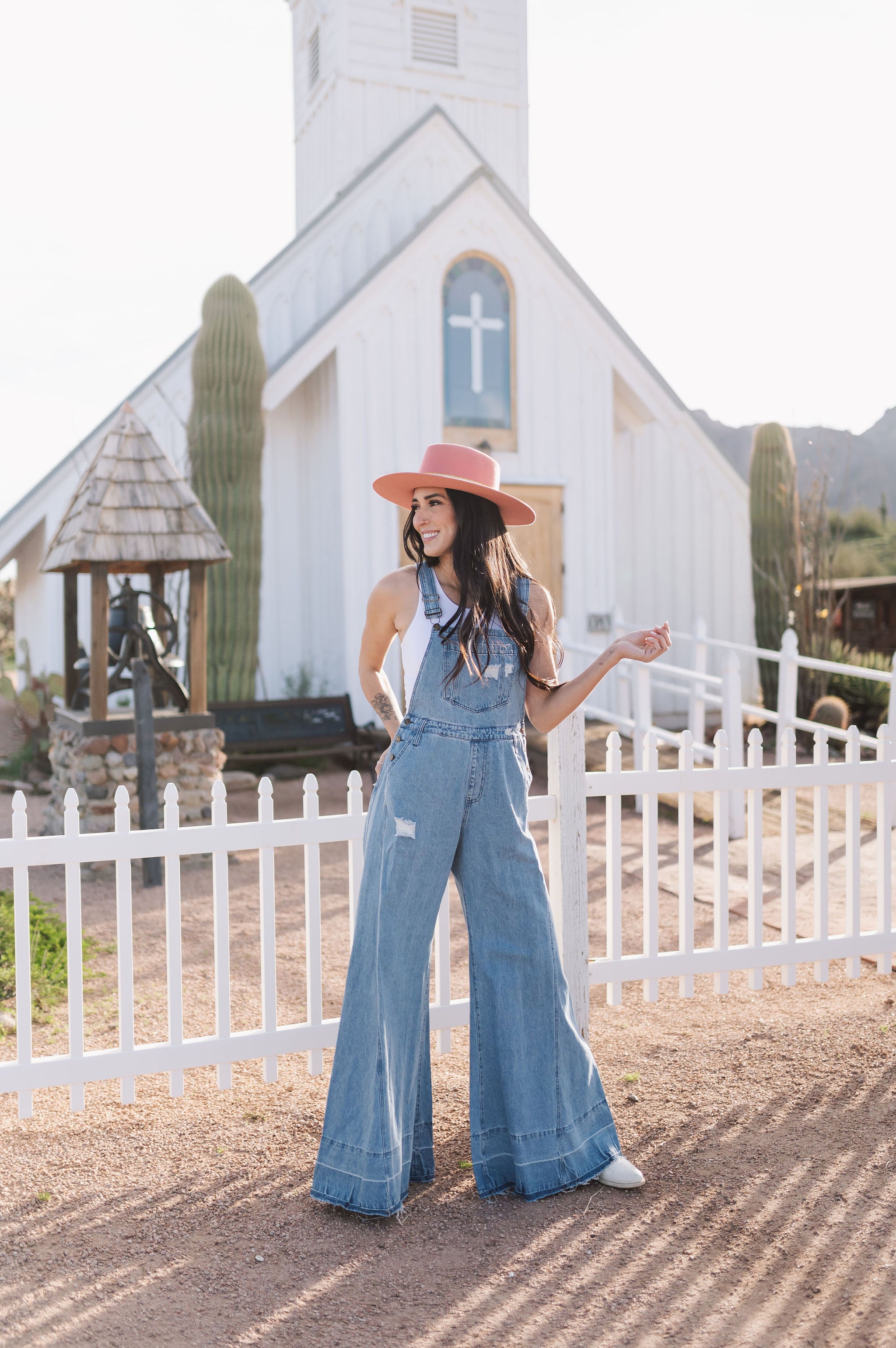 Front view of Clementine Wide Leg Distressed Denim Overalls with raw hem and front and side pockets.
