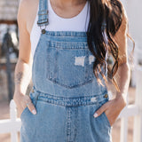 Close up front view of Clementine Wide Leg Distressed Denim Overalls with adjustable straps, front and side pockets, and heavy distressing details. 