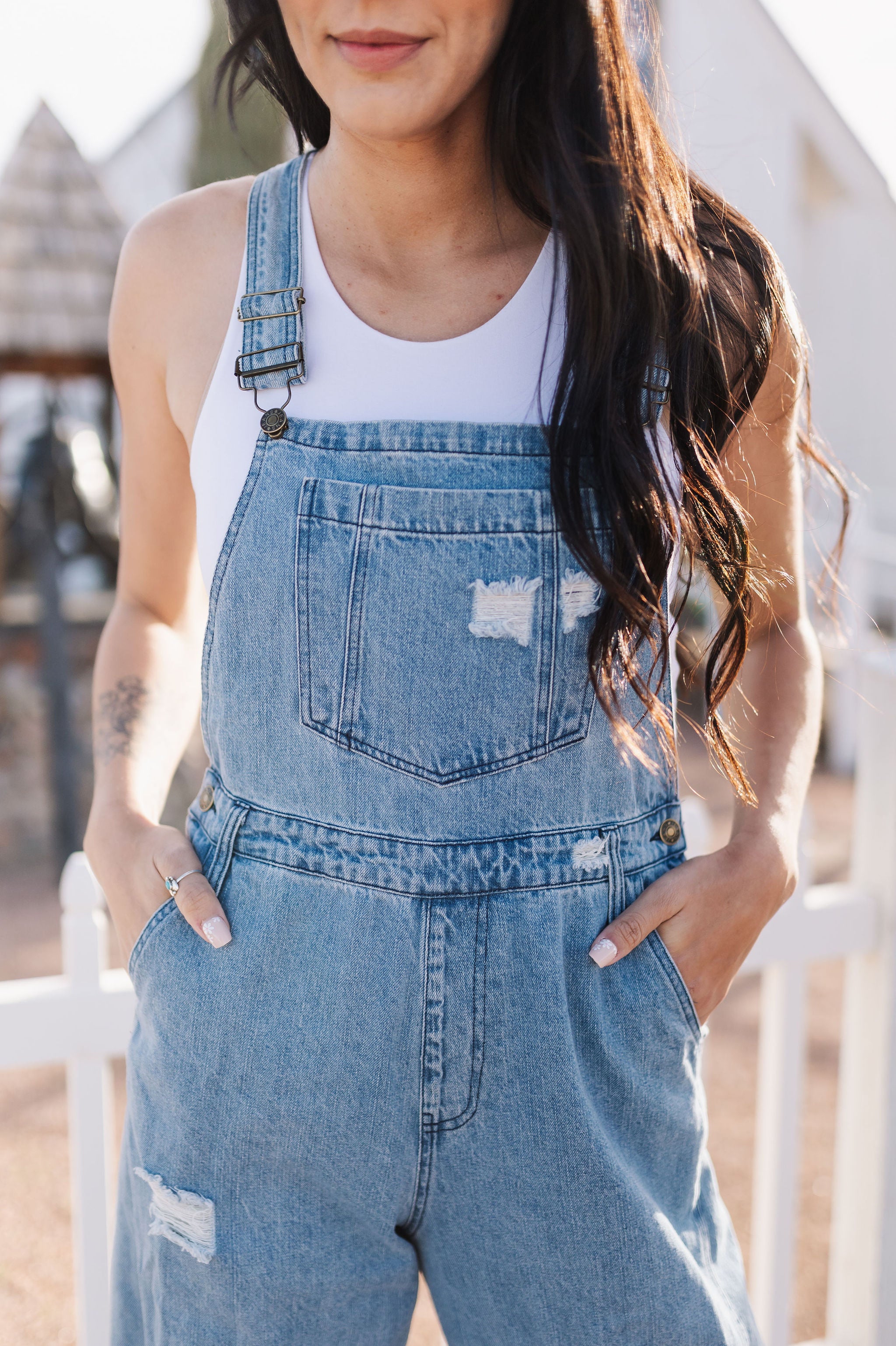 Close up front view of Clementine Wide Leg Distressed Denim Overalls with adjustable straps, front and side pockets, and heavy distressing details. 