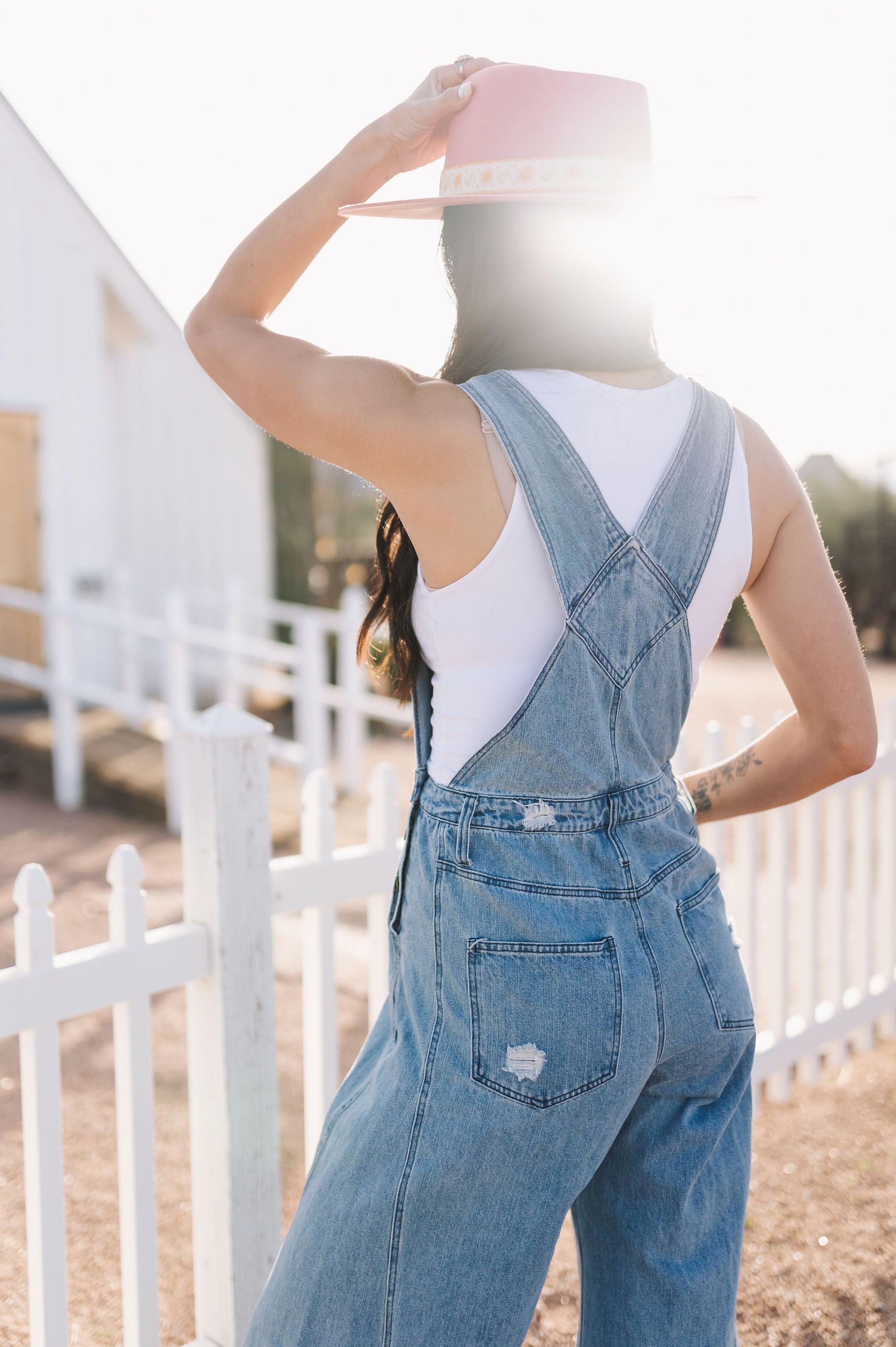 Close up rear view of Clementine Wide Leg Distressed Denim Overalls with back pockets. 