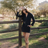 Front angled view of Outlaw Long Sleeve Dress in dark denim with zippered closure, belt, large pockets, and collared neck. 